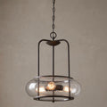 Industrial 3-light pendant with clear seeded glass and dark bronze metal frame on a neutral background.