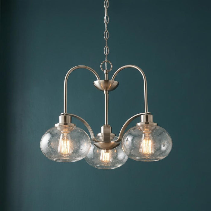 Brushed nickel 3-light chandelier with clear seeded glass globes against a dark teal wall.
