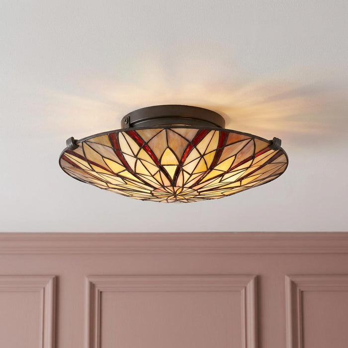 Circular Tiffany semi-flush ceiling light with geometric stained glass floral pattern.