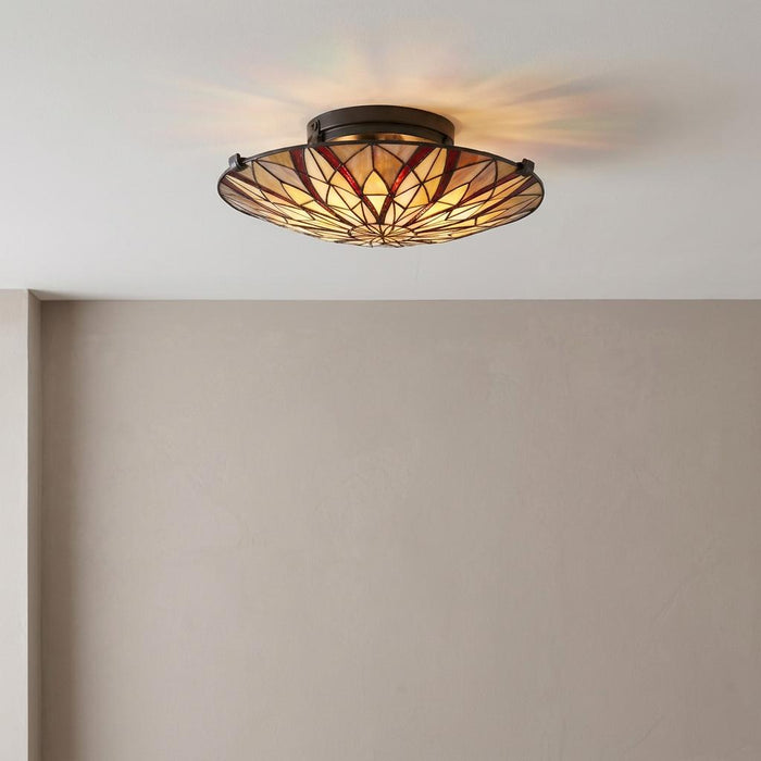 Geometric cream and red Tiffany semi-flush ceiling light glowing against a white ceiling and beige wall.