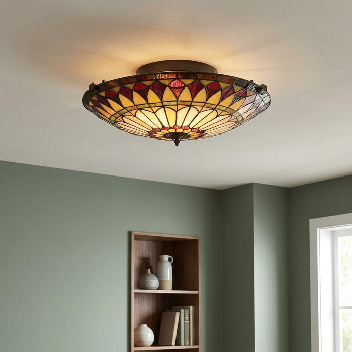 Illuminated Tiffany-style stained glass flush mount ceiling light with a yellow and red sunburst pattern.