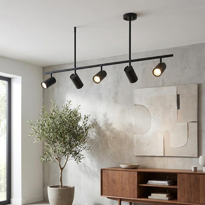 A five-light black modern bar spot light mounted on a ceiling in a contemporary living room.