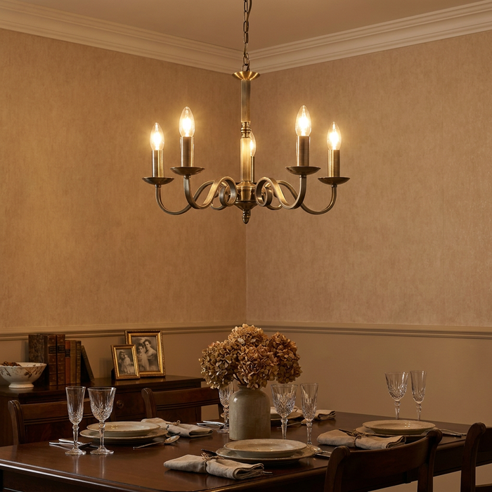 Antique brass 5-light chandelier with scroll arms illuminating a classic dining room setting.