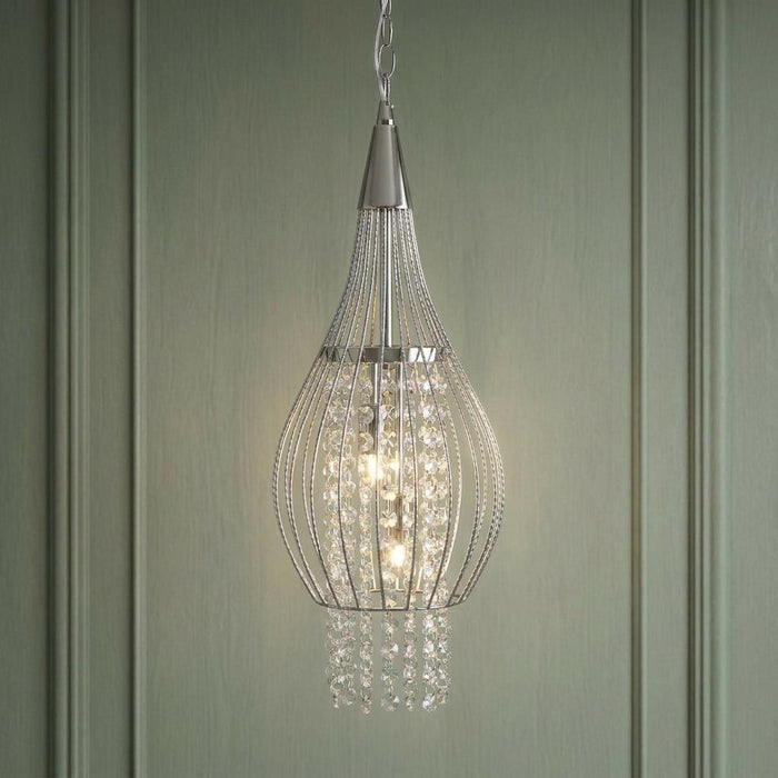 Chrome cage frame ceiling pendant with internal crystal strings and two lit bulbs against a green paneled wall.