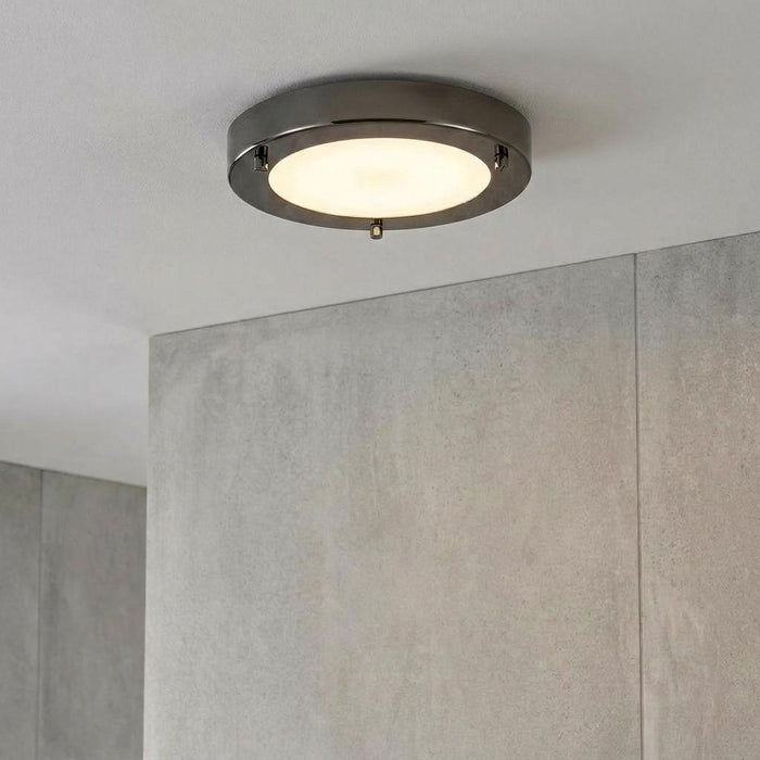 Rondo Mirror Black flush ceiling light with a glowing frosted diffuser on a white ceiling above a grey tiled wall.