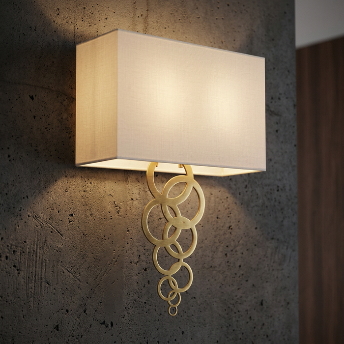 Aged brass wall light with a rectangular white shade and cascading rings mounted on a textured concrete wall.