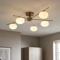 Antique brass semi-flush ceiling light with five opal glass globe shades on slender metal arms.