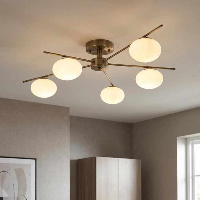 Antique brass semi-flush ceiling light with five opal glass globe shades on slender metal arms.