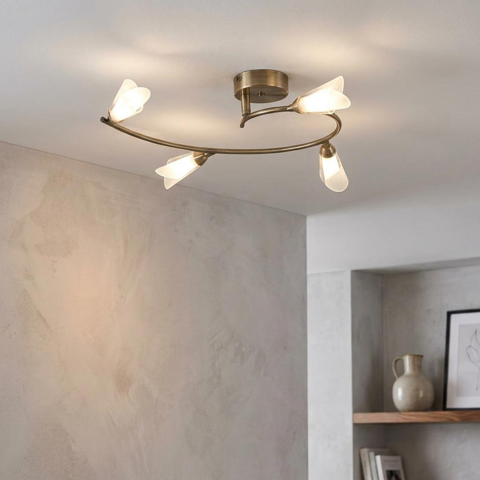 Sare 4 light antique brass flush ceiling fixture with frosted tulip shades on a curved arm.