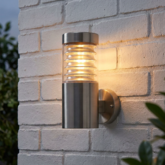 Saxby Endon Equinox brushed steel outdoor wall light with louvred diffuser, illuminated on a white brick wall.