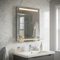 Modern LED bathroom mirror with illuminated shelf and top light bar, mounted on marble wall above a white vanity sink.