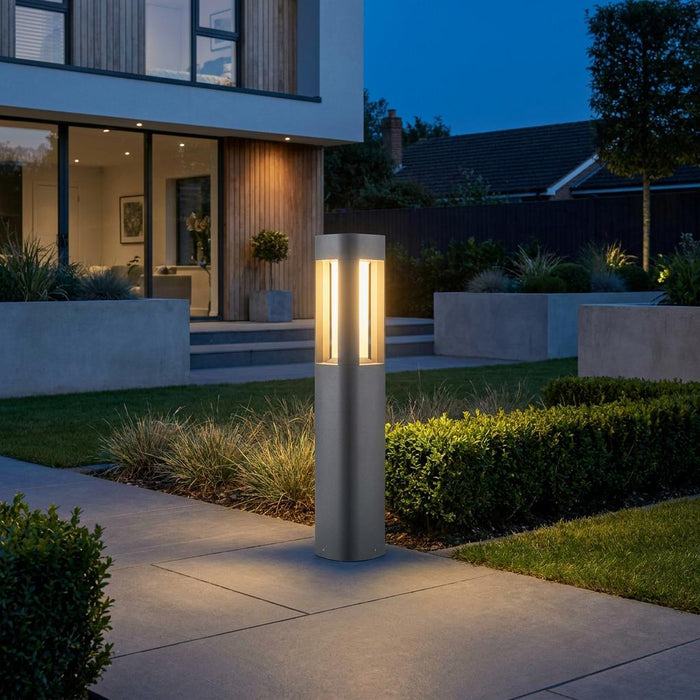Sleek grey LED bollard light illuminating a modern garden path at dusk.