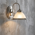 Silver wall sconce with a ribbed glass shade and pull cord, illuminated against a textured grey wall.