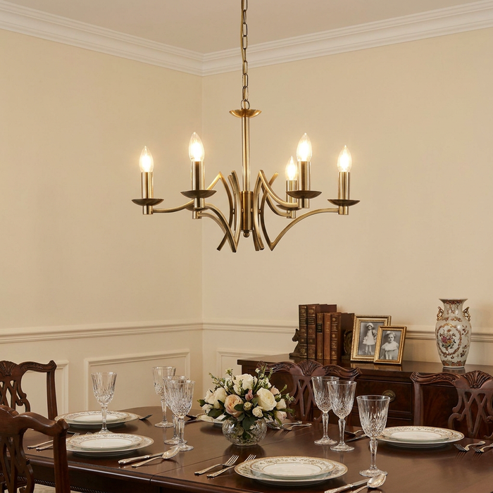 Antique brass 6-light chandelier with curved arms hanging above a set formal dining table.