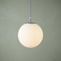 Atom silver and opal glass globe pendant light hanging against a sage green background.