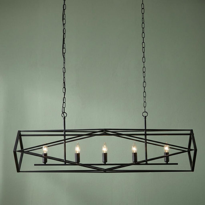 Black geometric cage 5-light pendant with candle bulbs suspended by chains against a light green background.