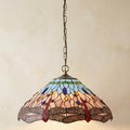 Dragonfly Tiffany ceiling light with blue and pink stained glass hanging from a brass chain against a beige wall.