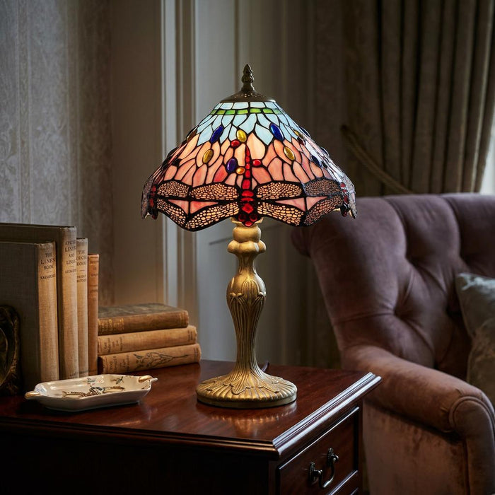 Dragonfly Tiffany table lamp with a colourful stained glass shade on a wooden side table in a cosy room.