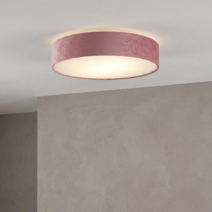 Pink velvet drum flush ceiling light with a white diffuser, glowing on a white ceiling.