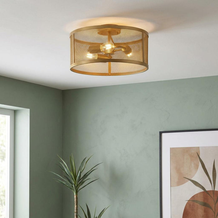 Modern gold fishnet drum ceiling light fixture on a white ceiling in a room with light green walls.