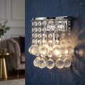 Lit Searchlight Hanna 2 light chrome wall sconce with cascading crystal balls on blue patterned wallpaper.