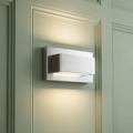 Modern rectangular chrome up and down wall light glowing on a sage green paneled wall.