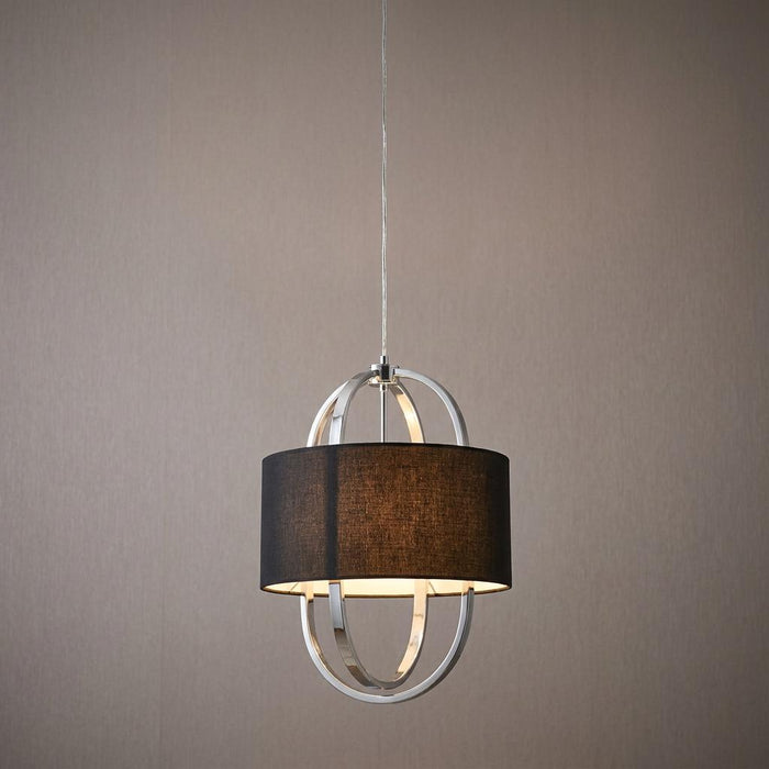Chrome orbital pendant light with a black fabric drum shade, illuminated against a neutral wall.