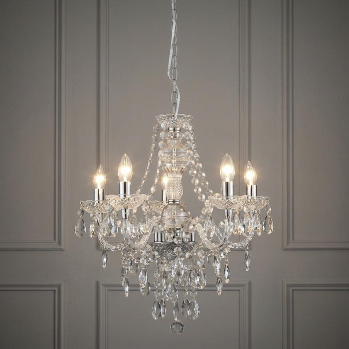 Searchlight Marie Therese 5 Light Clear Acrylic Chandelier hanging against a grey panelled wall.