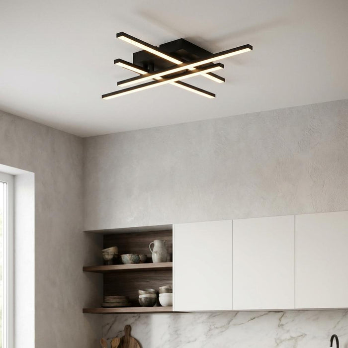 Modern black LED ceiling light with four intersecting bars illuminated in a contemporary kitchen.
