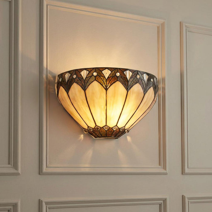 Illuminated Tiffany wall light with cream glass panels and decorative dark trim on a white paneled wall.