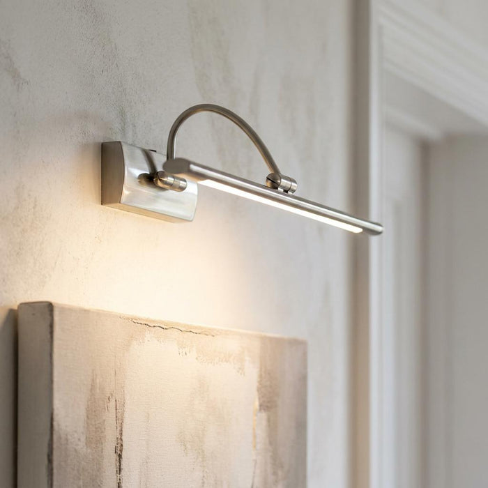 Satin silver LED picture light with an adjustable arched arm illuminating abstract wall art.