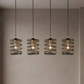 Four black and gold spiral pendant lights with exposed bulbs hanging against a neutral wall.