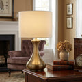 Antique brass touch lamp with a cream cylinder shade sits on a wooden side table in a cozy living room.