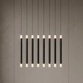 Linear pendant with eight black wands and glowing frosted tips, suspended against a neutral wall.