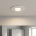 White ShieldSLIM recessed ceiling light casting a warm glow from a plain white ceiling in a blurred kitchen setting.