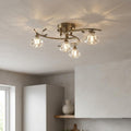 Four-light brass semi-flush ceiling light with faceted crystal shades and leaf details on a white ceiling.