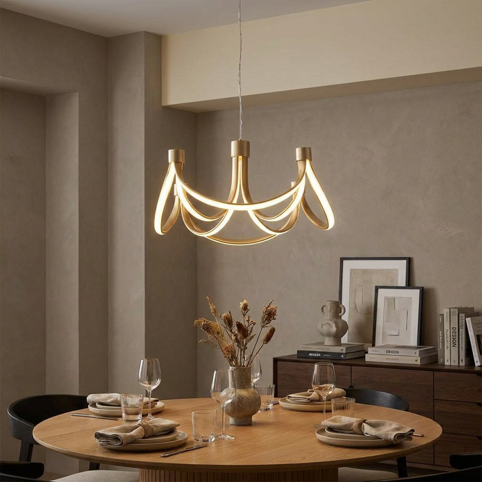 Modern gold 8-arm LED pendant light with looping arms hanging over a wooden dining table in a minimalist room.