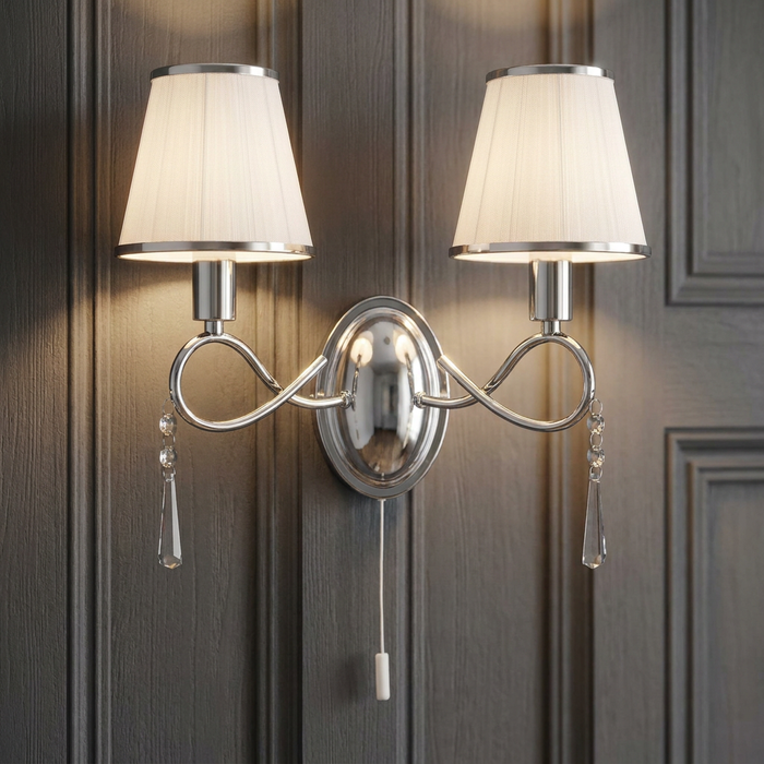 Chrome 2-light wall sconce with white pleated shades and crystal droplets on a dark paneled wall.