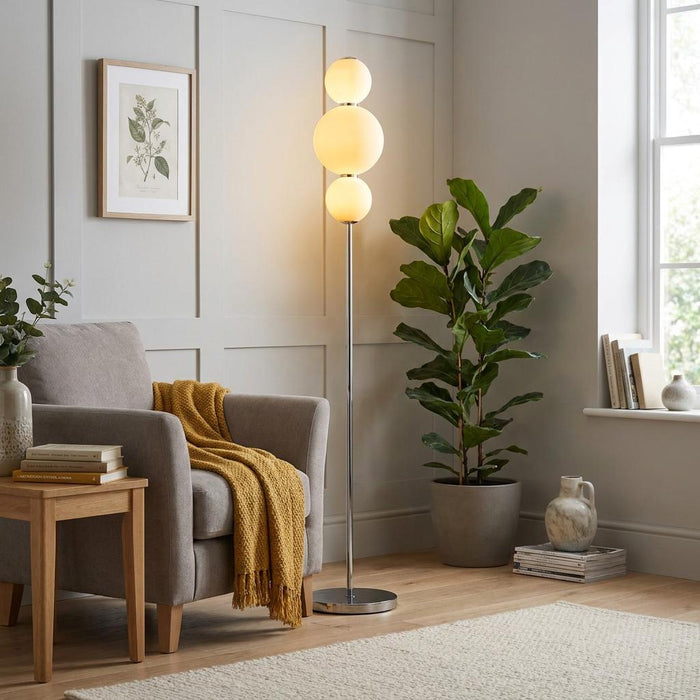 Snowball Art Deco Floor Lamp with three stacked opal globes in a cozy living room with a grey armchair.