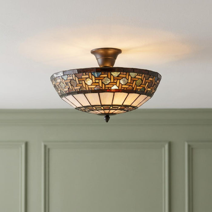 Tiffany semi-flush ceiling light with a patterned stained glass shade, glowing against a green paneled wall.