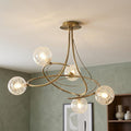 Tabia 5 light antique brass semi flush ceiling light with swooping arms and webbed glass globes in a modern room.