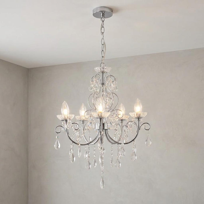 Tabitha crystal glass and chrome five-light chandelier with decorative droplets hanging against a neutral wall.