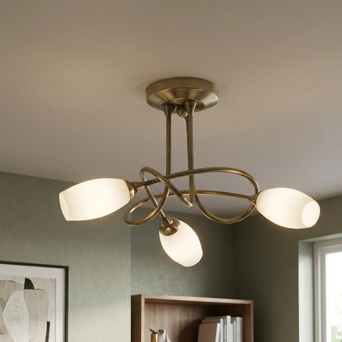 Tara 3-light antique brass semi-flush ceiling light with intertwined arms and opal glass shades in a modern room.