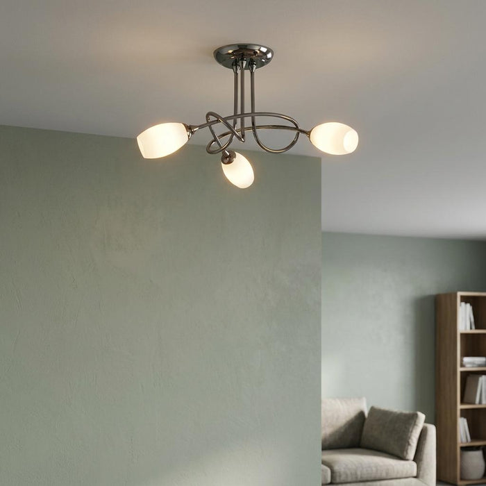 Modern black semi-flush ceiling light with three glowing opal glass shades against a sage green wall.