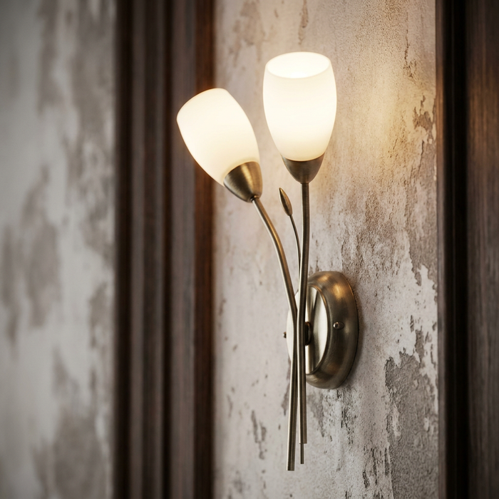 Antique brass wall light with two tulip-shaped frosted glass shades mounted on a rustic textured wall.