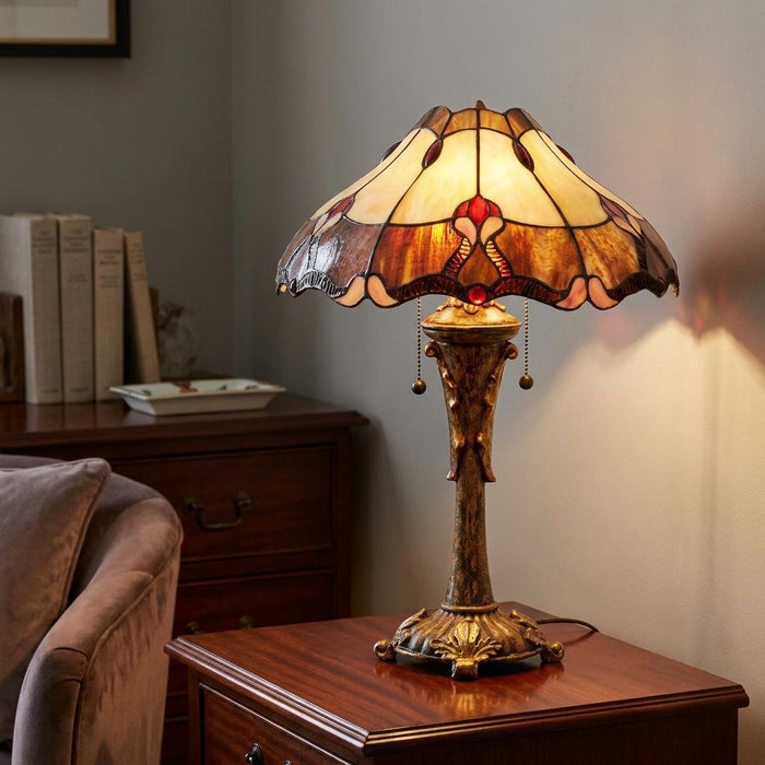 Lit Eastbourne Tiffany table lamp with a cream stained glass shade and ornate bronze base on a dark wood side table.