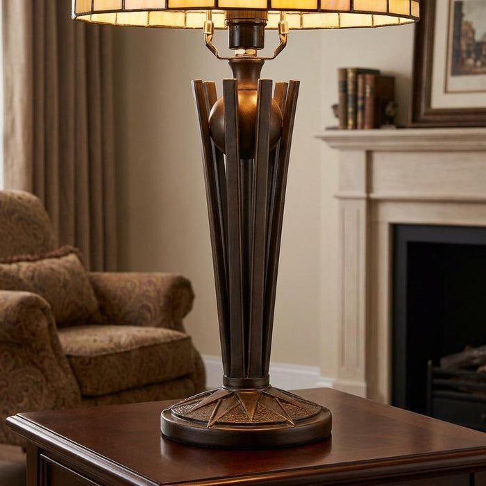 Bronze Art Deco Tiffany lamp base with flared columns and starburst detail on a wooden table in a living room.