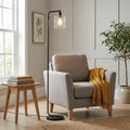 Toledo Black Floor Lamp with a clear glass shade stands next to a grey armchair with a yellow throw in a living room.