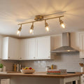 Torne antique brass 4-light ceiling bar with clear glass shades mounted over a modern kitchen island.