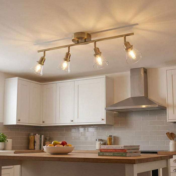 Torne antique brass 4-light ceiling bar with clear glass shades mounted over a modern kitchen island.